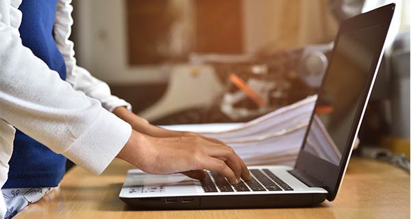 A person typing on a laptop to manually enter data. If she makes a mistake, the consequences could be costly.