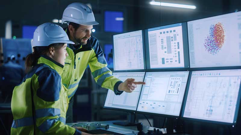 Two employees overseeing a programmable logic controller (PLC) control system.