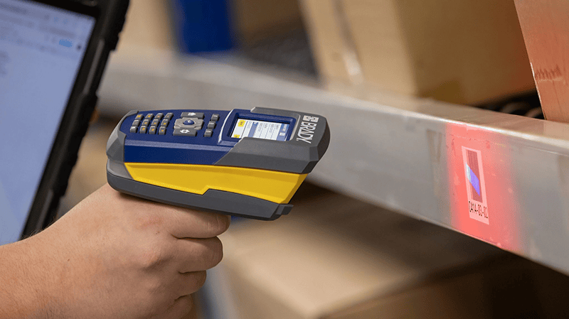 A warehouse worker takes inventory of shelved products using a barcode scanner.